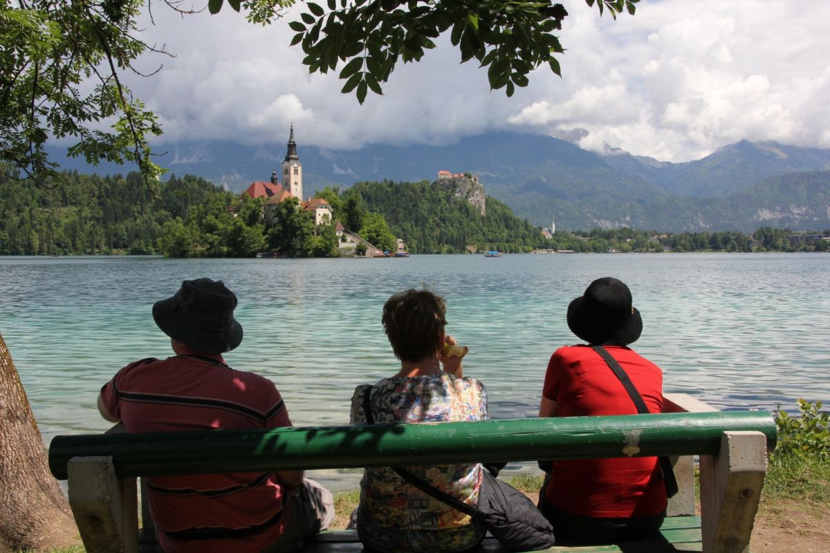 a double trio.. three happy tourists watching an island with church, a castle on a cliff and the main Bled church.. a double trio.. three happy tourists watching an island with church, a castle on a cliff and the main Bled church..